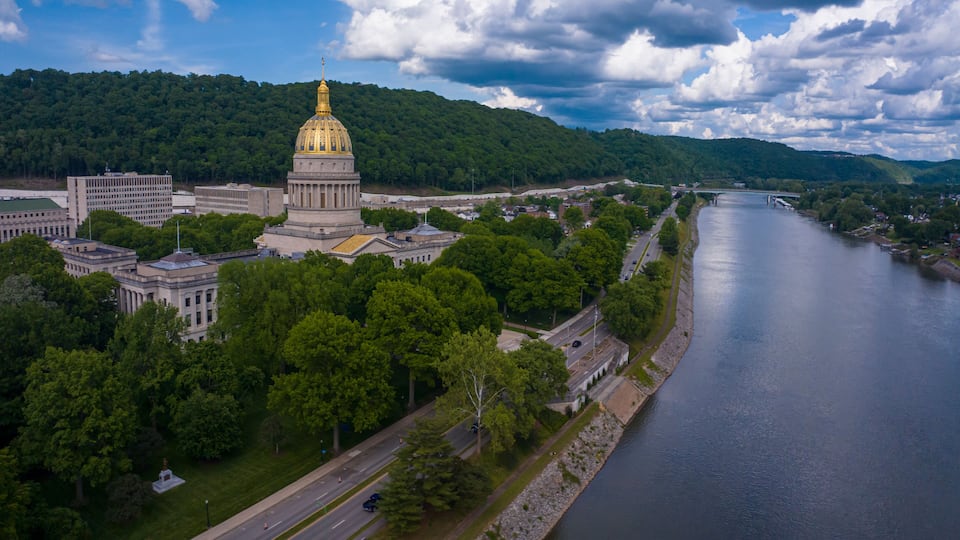 A river, a large building with a golden dome, and a forested hill.