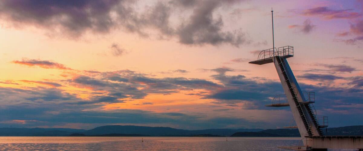 A sunset over a calm lake with a pier extending into the water.