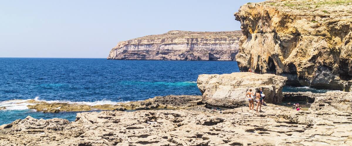 A rocky coastline with cliffs and a clear blue sea.