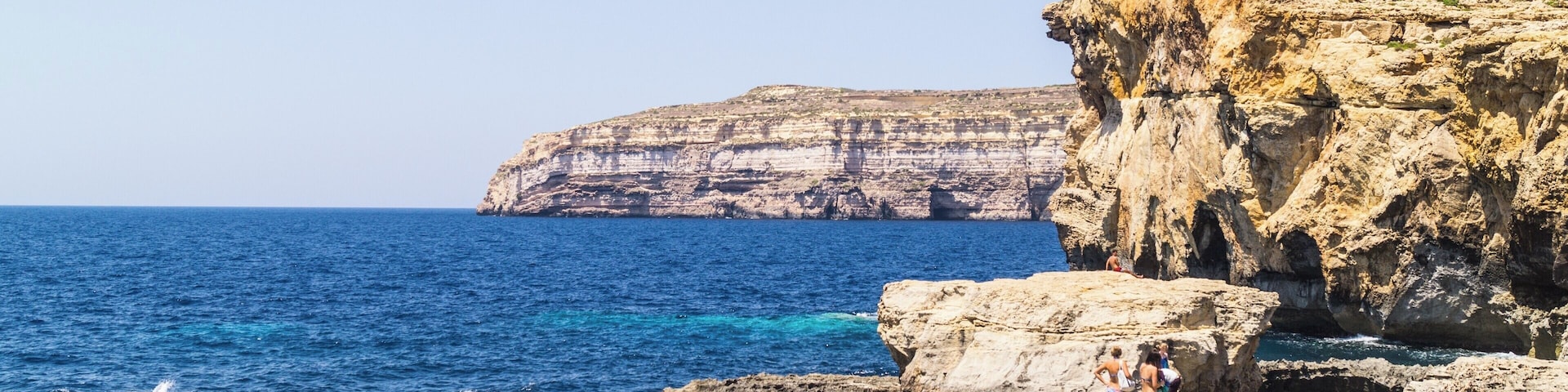 A rocky coastline with cliffs and a clear blue sea.