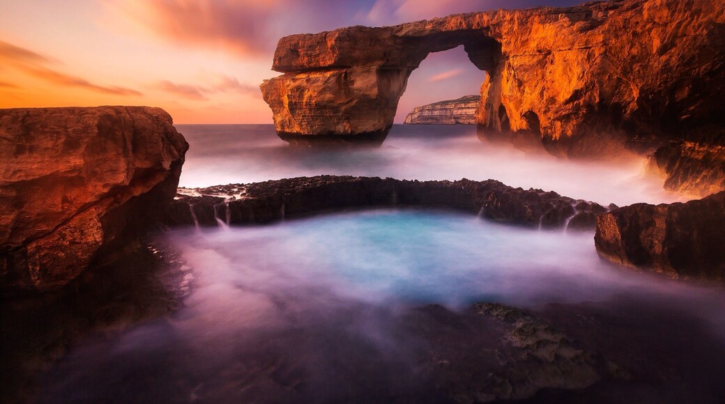 The Azure Window on the island of Gozo in Malta is a wonderful place to watch the sun set on a warm summer's evening. The site also offers some excellent scuba diving. It might also be interesting to know that parts of the popular tv series Game of Thrones was shot there.