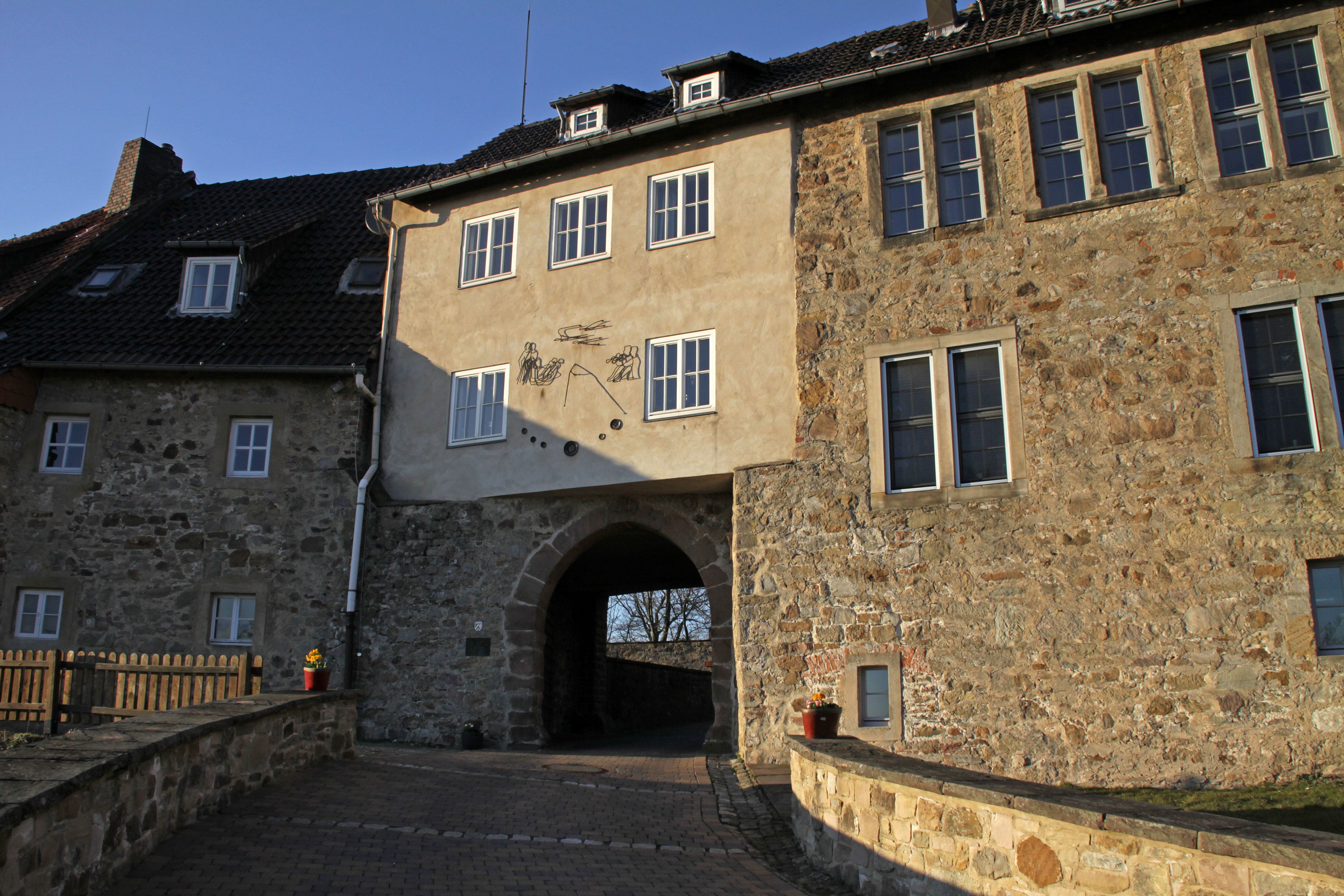 A stone building with multiple windows and a large archway entrance.