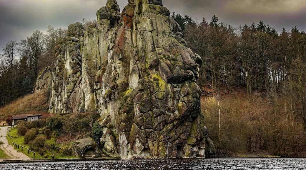 A large rock formation with a path leading to a small building.