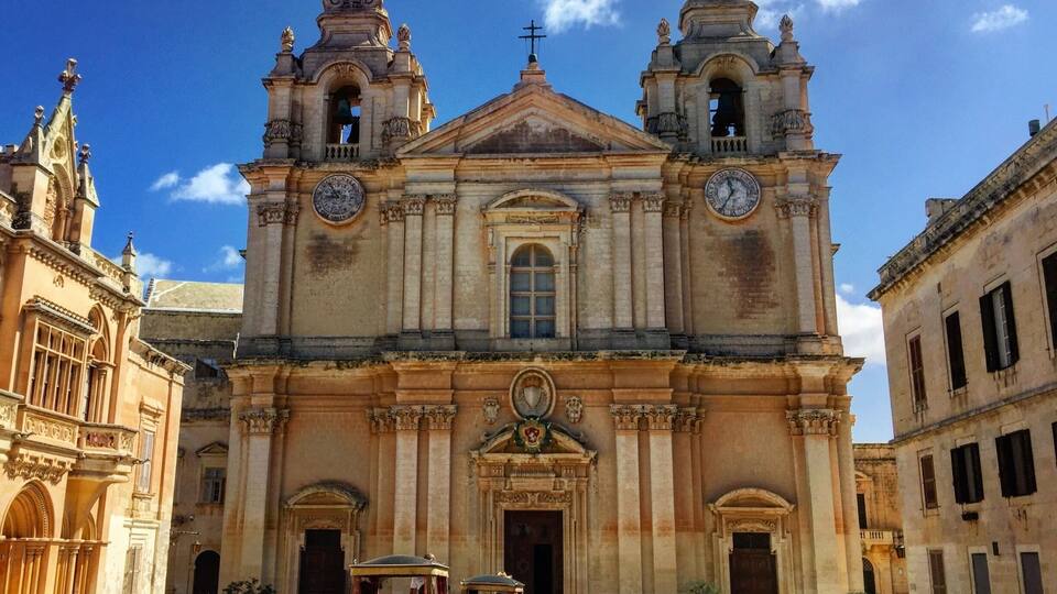 A historic church with two bell towers and a central dome, surrounded by old buildings.