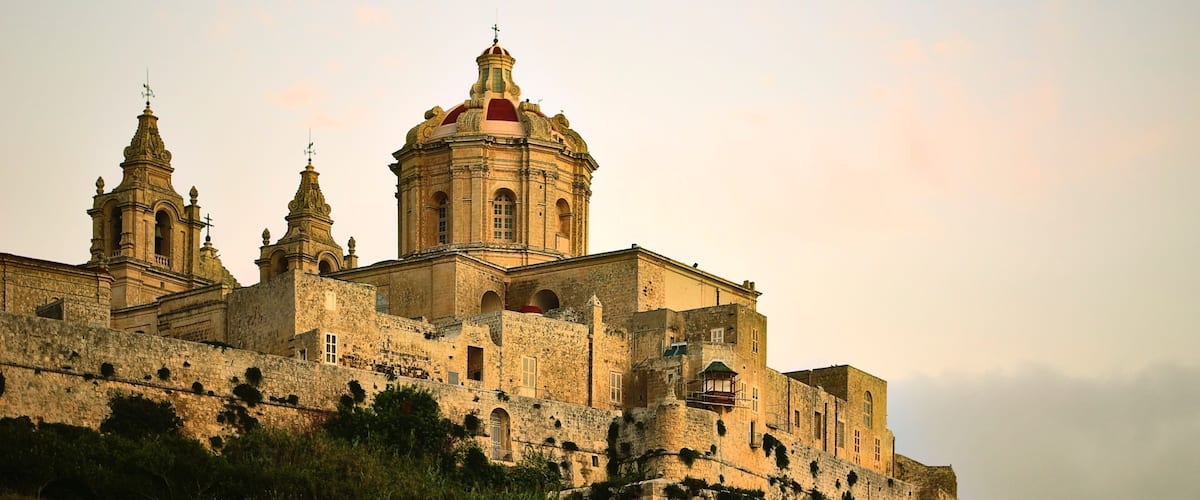 A historic church with a prominent dome and two bell towers, surrounded by a fortified wall.