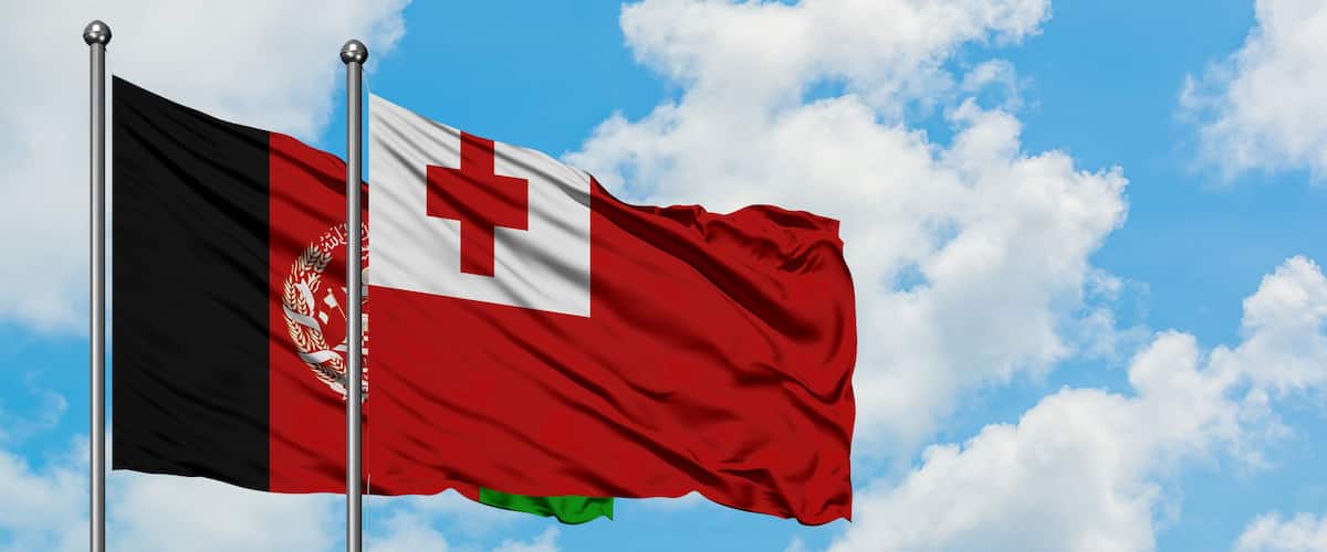 A flag on a flagpole against a blue sky with clouds.