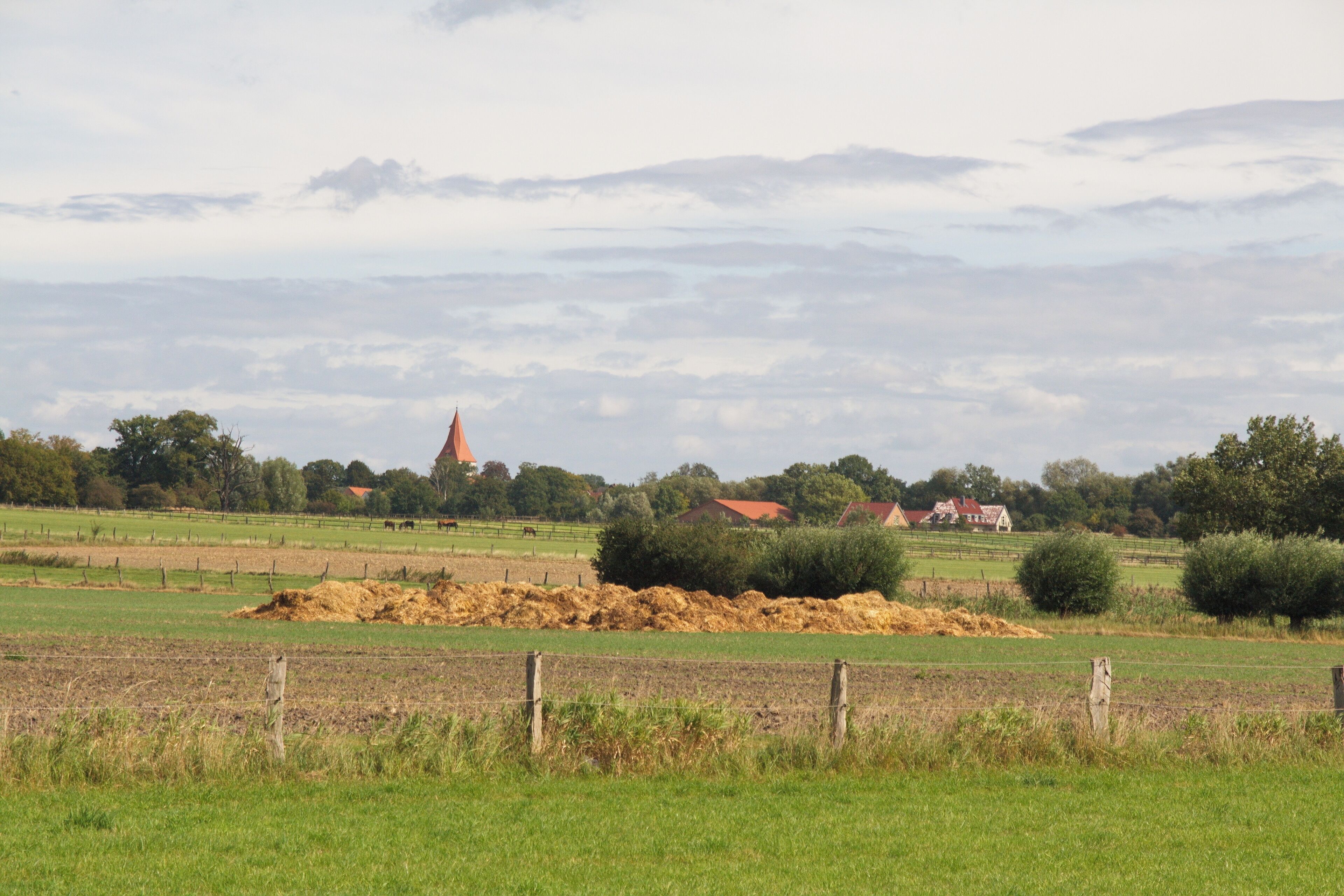 Paisaje rural con campos, una iglesia y casas.