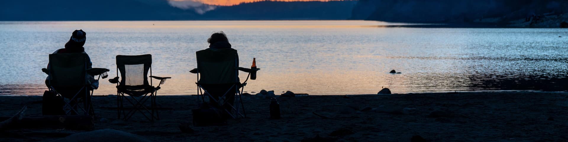 Garibaldi provincial park. Unrecognizable people by the lake with turquoise water at sunset. Snow mountain at the background. Hikers on the trail. British Columbia, Canada.