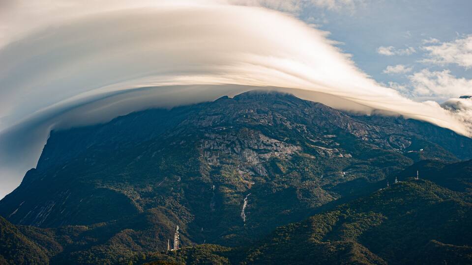 A mountain with a cloud formation over it.