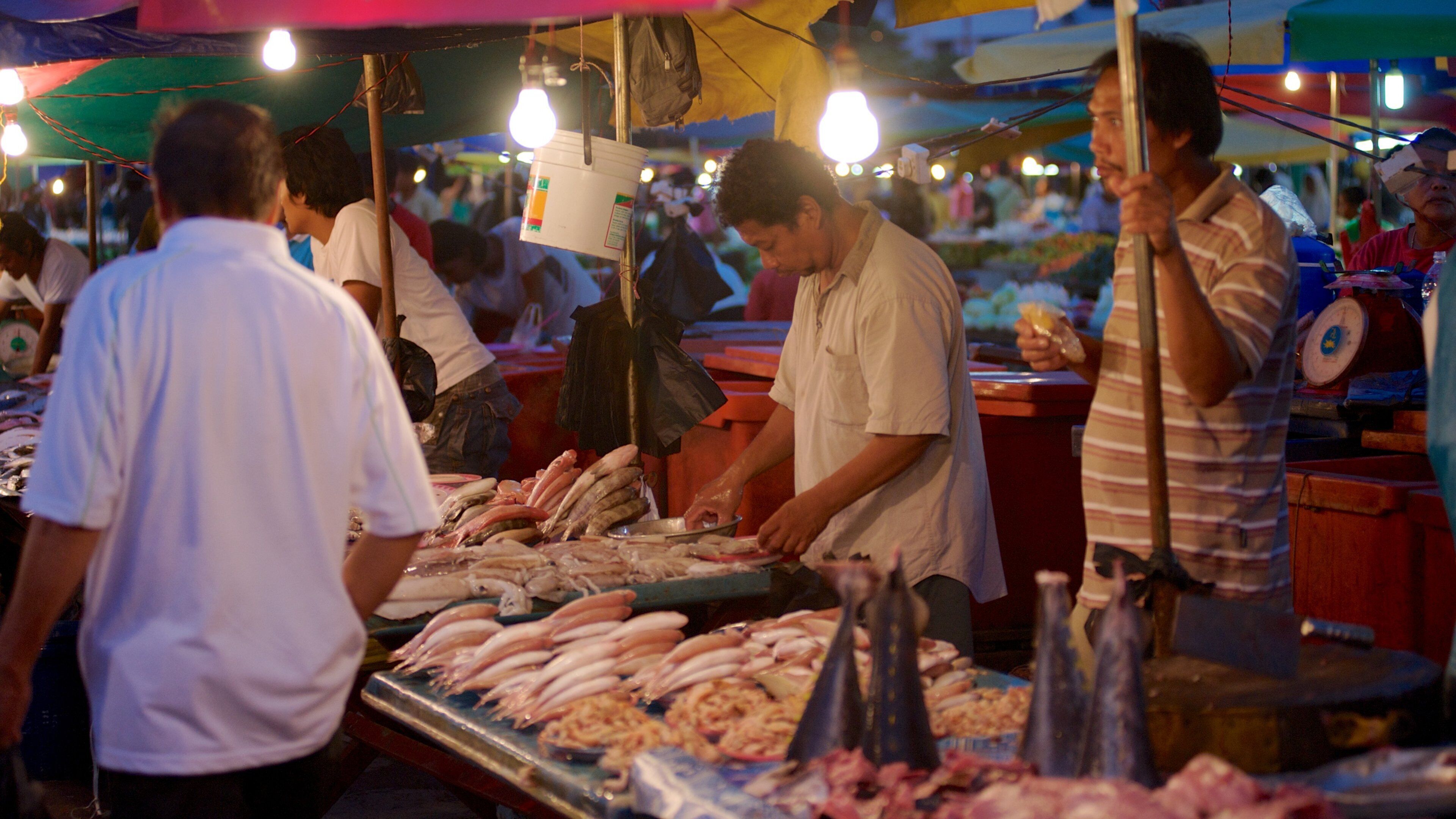 A bustling fish market with vendors selling various seafood items.