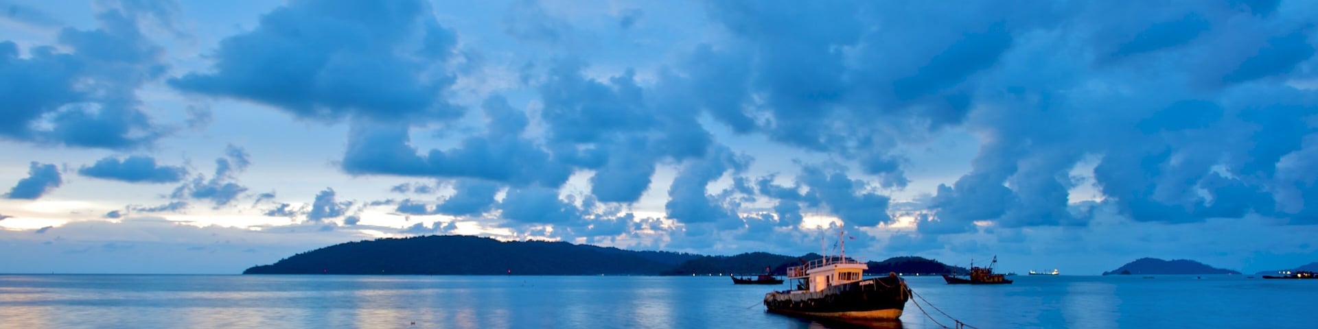 A calm sea with a boat anchored near a small island.
