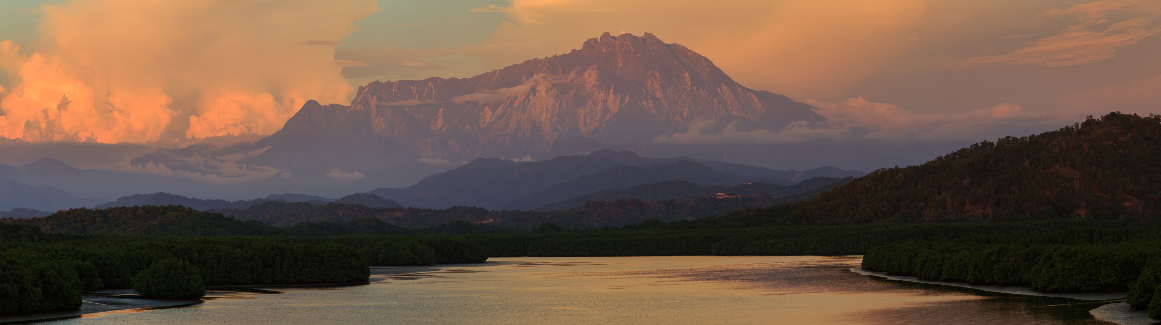 A river winding through a forested valley with a prominent mountain range in the background.