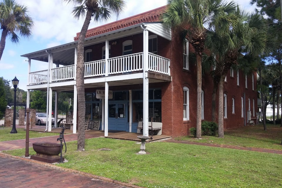 A two-story brick building with a white balcony and a covered porch.