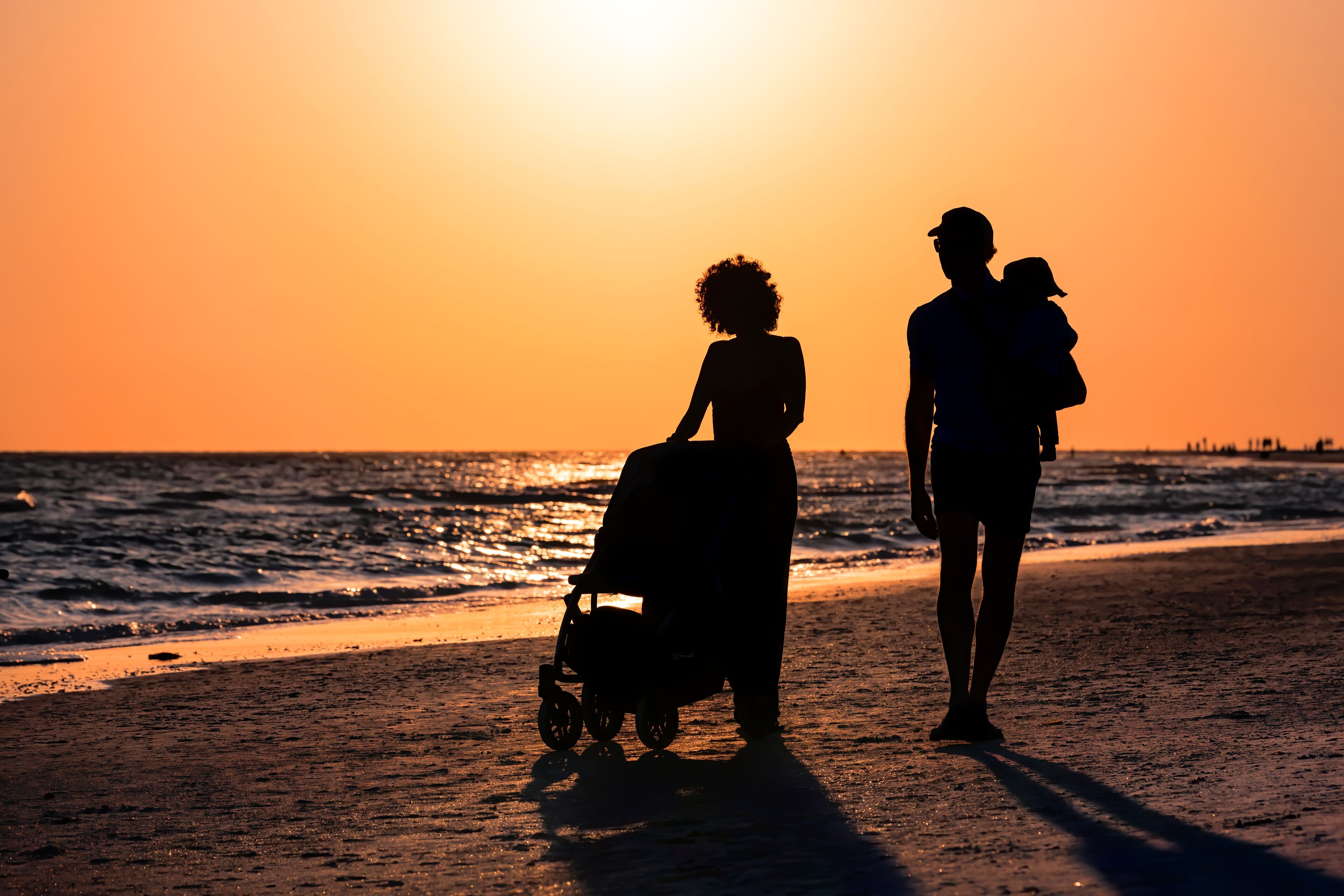 Sunset in Siesta Key, Florida near Sarasota, USA with coastline coast ocean gulf of mexico, young couple silhouette walking on beach shore