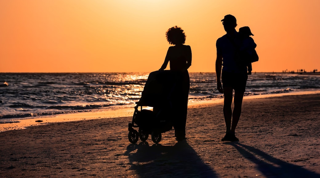 Sunset in Siesta Key, Florida near Sarasota, USA with coastline coast ocean gulf of mexico, young couple silhouette walking on beach shore