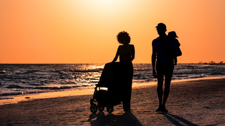 Silhouettes of a family on a beach at sunset.