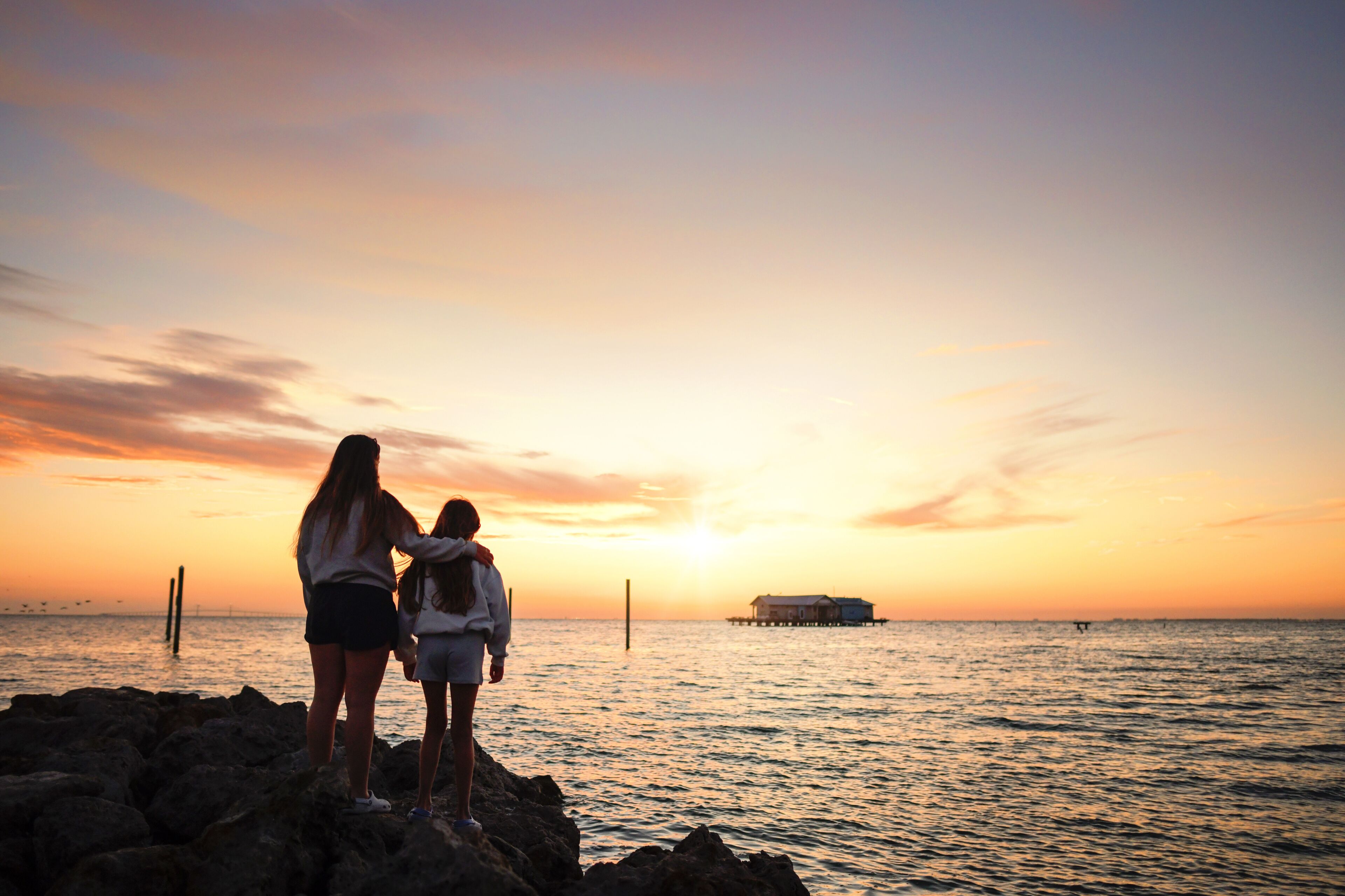 Behind teen sisters standing watching beautiful sunrise Anna Mar
