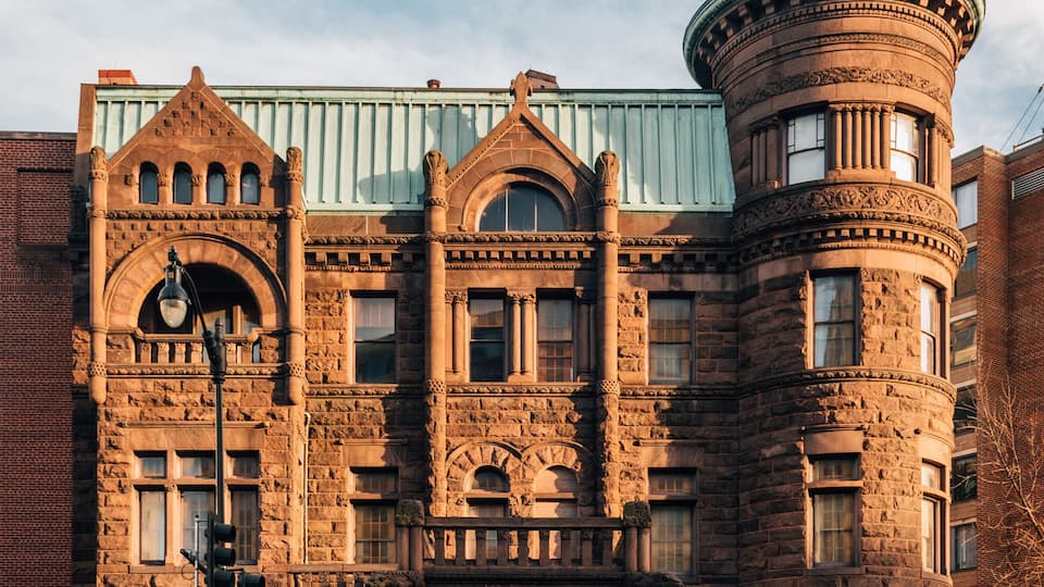 A historic stone building with a turret and arched windows.