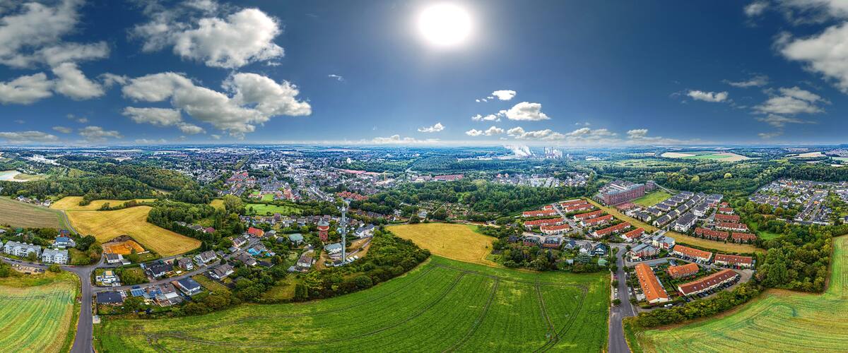 An aerial view of a town with fields, houses, and a large body of water in the distance.