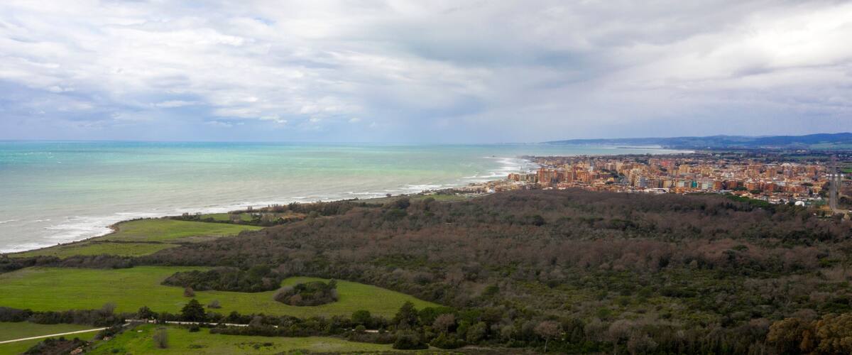 A coastal cityscape with a beach, dense urban area, and surrounding greenery.