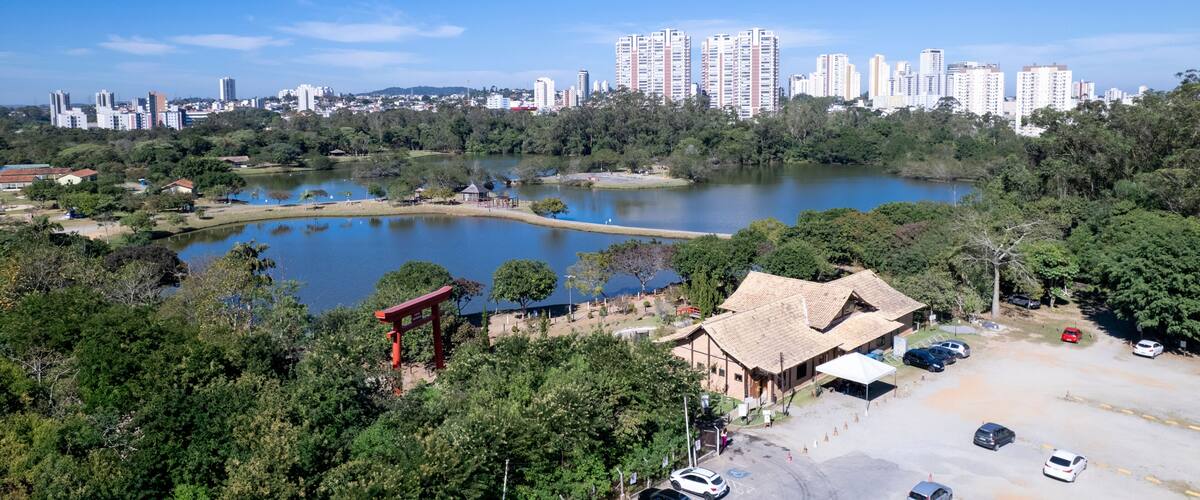 A park with a lake, a red torii gate, and a cityscape with high-rise buildings in the background.