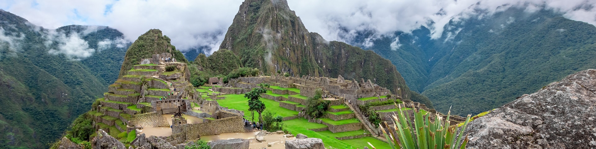 Machu Picchu, una ciudad incaica antigua con campos en terrazas y estructuras de piedra, rodeada de montañas cubiertas de niebla.