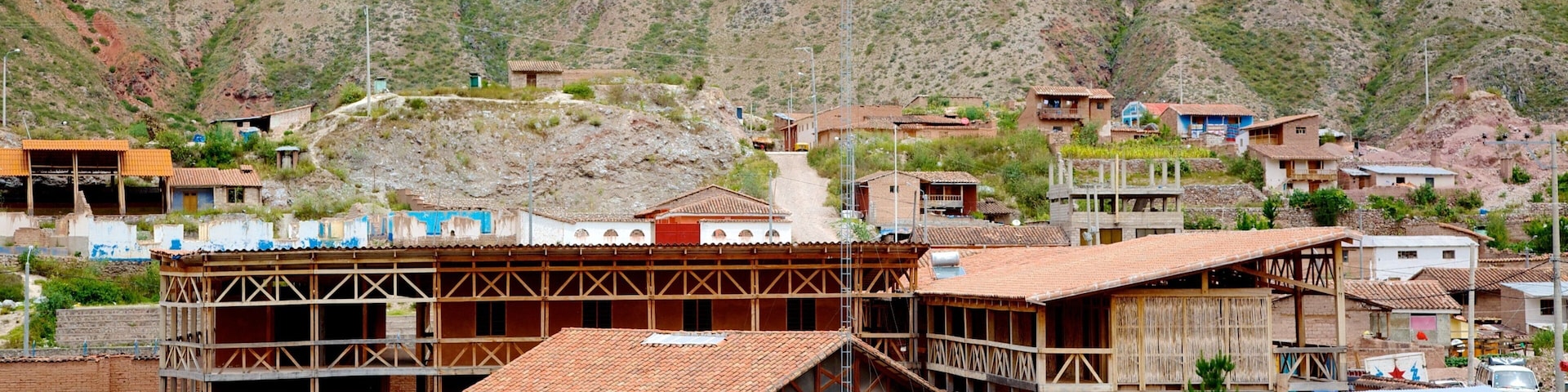A rural market with blue canopies and a mountainous backdrop.