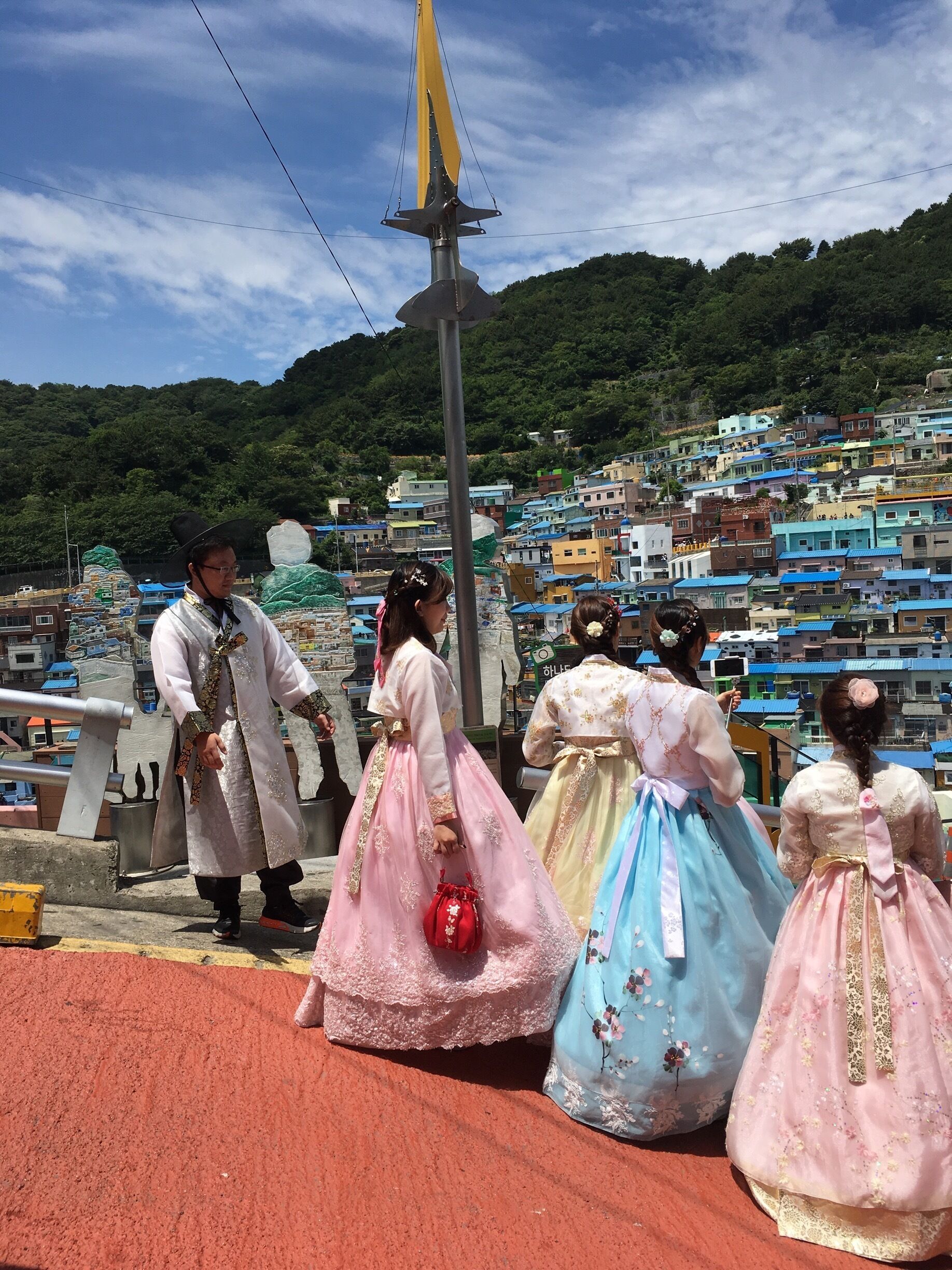 A group of people in traditional attire on a bridge with a cityscape in the background.