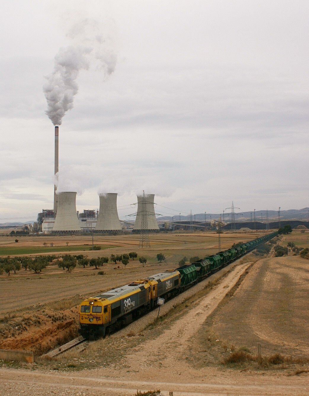 Últim mercant que vam poder fotografiar al ramal de la central tèrmica d'Andorra, el següent el van suprimir degut a que les japoneses que el pujaven cap a Samper de Calanda es van quedar avariades. Degut a això la 319.250 i la 319.251 van baixar un tall de 32 tremuges per finalitzar la tanda de carboners de la tarda. Último mercante que pudimos fotografiar en el ramal de la central térmica de Andorra, el siguiente lo suprimieron debido a que las japonesas que lo subían a Samper de Calanda se quedaron averiadas. Debido a esto la 319.250 y la 319.251 se bajaron un corte de 32 tolvas para finalizar la tanda de carboneros de la tarde.