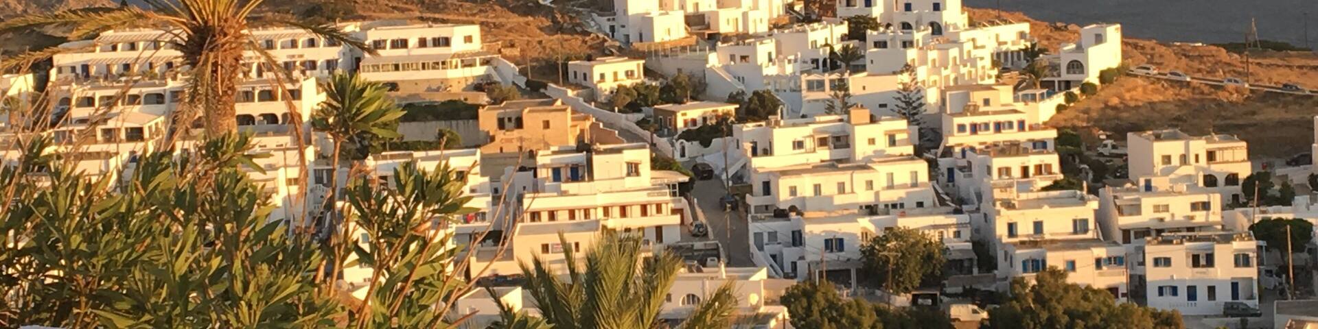 A coastal village with white buildings, a palm tree, and rocky terrain.