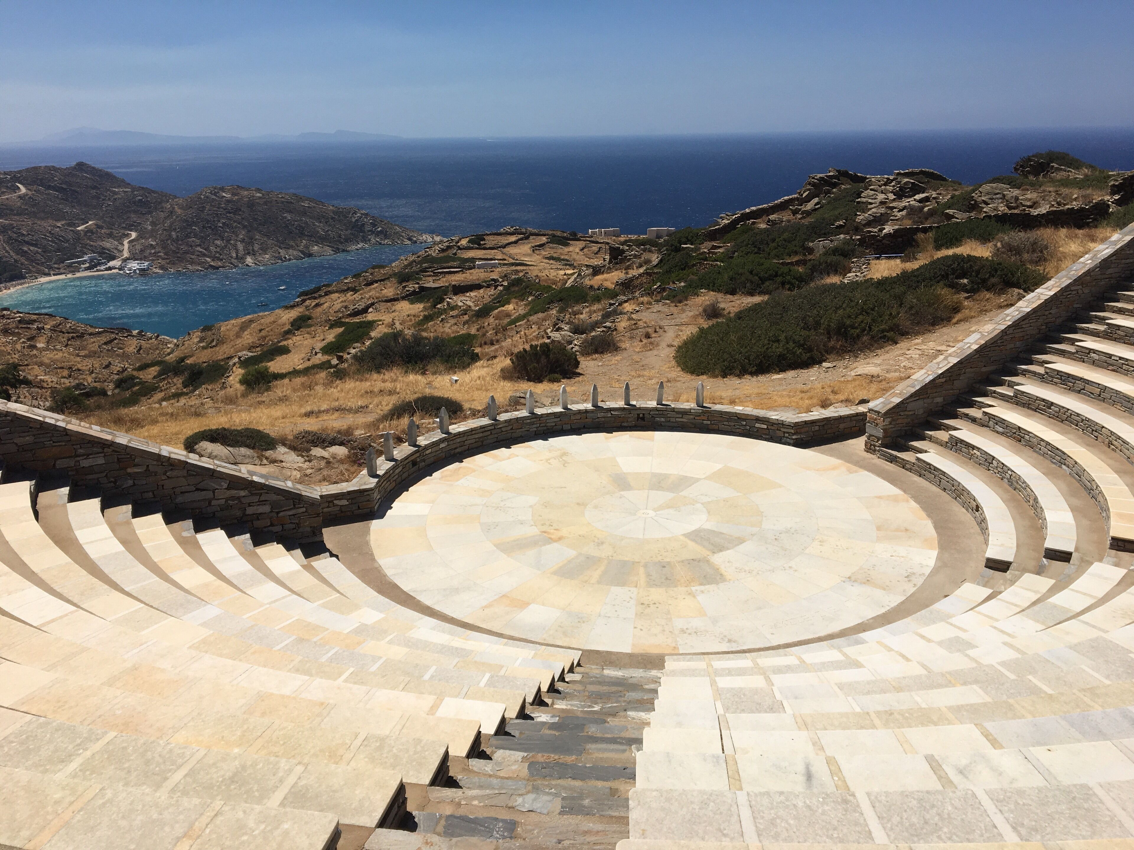 A stone amphitheater with a view of the sea and mountains.