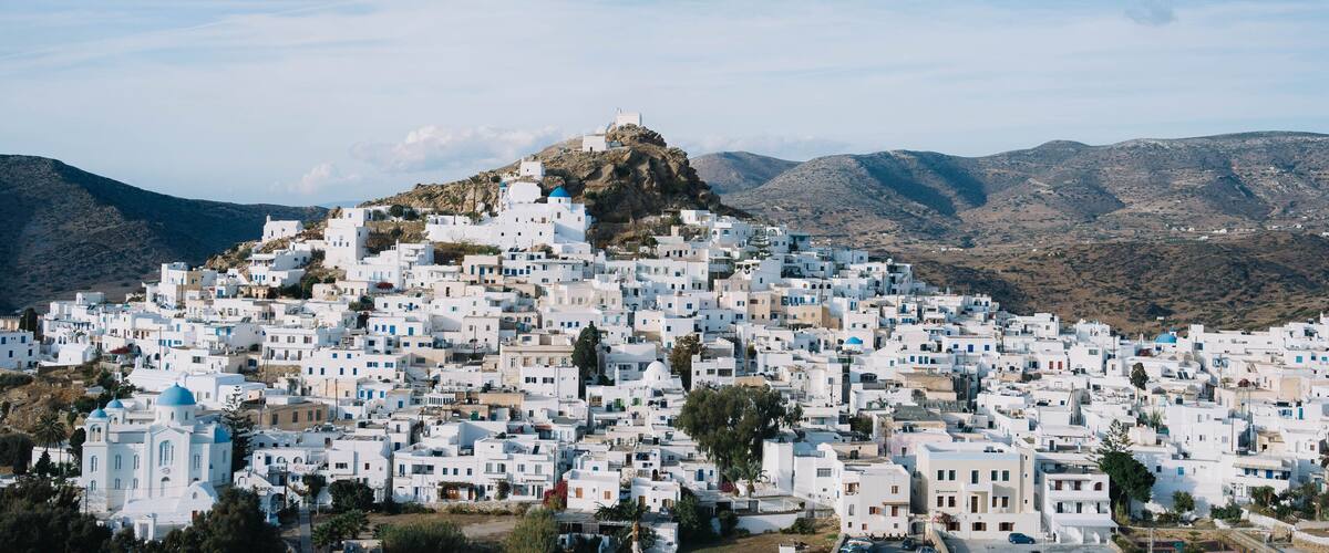 A densely packed white village on a hillside with a prominent church at the top.