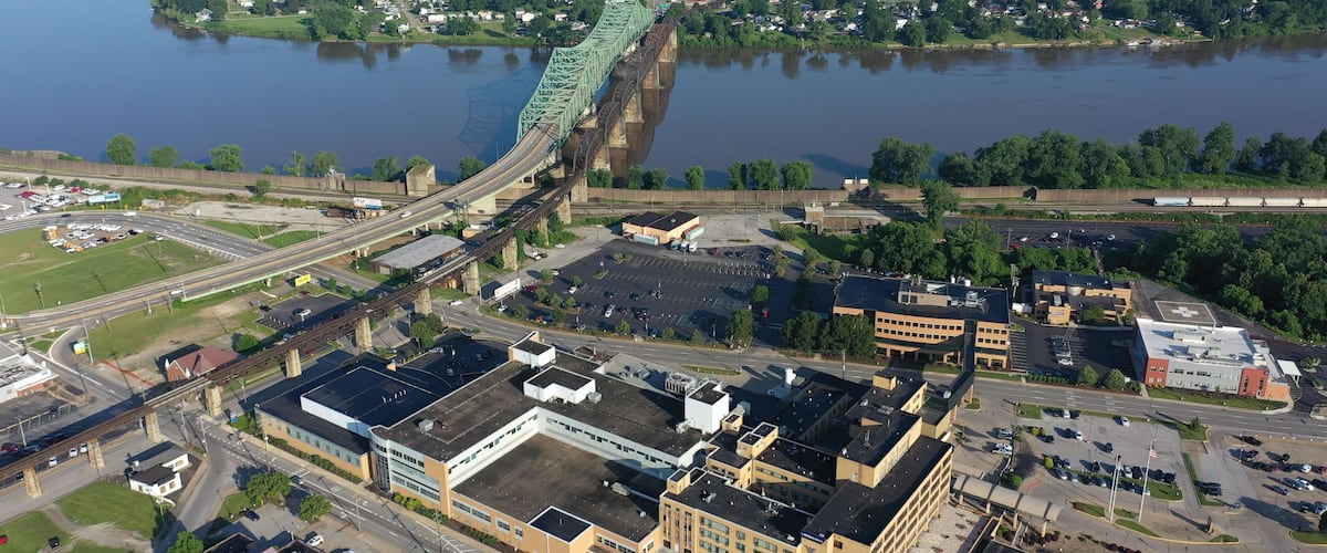 A river with a bridge, a parking lot, and buildings.