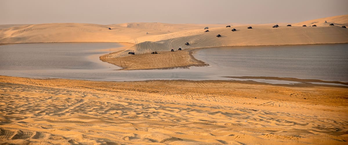 A desert landscape with sand dunes and a body of water.