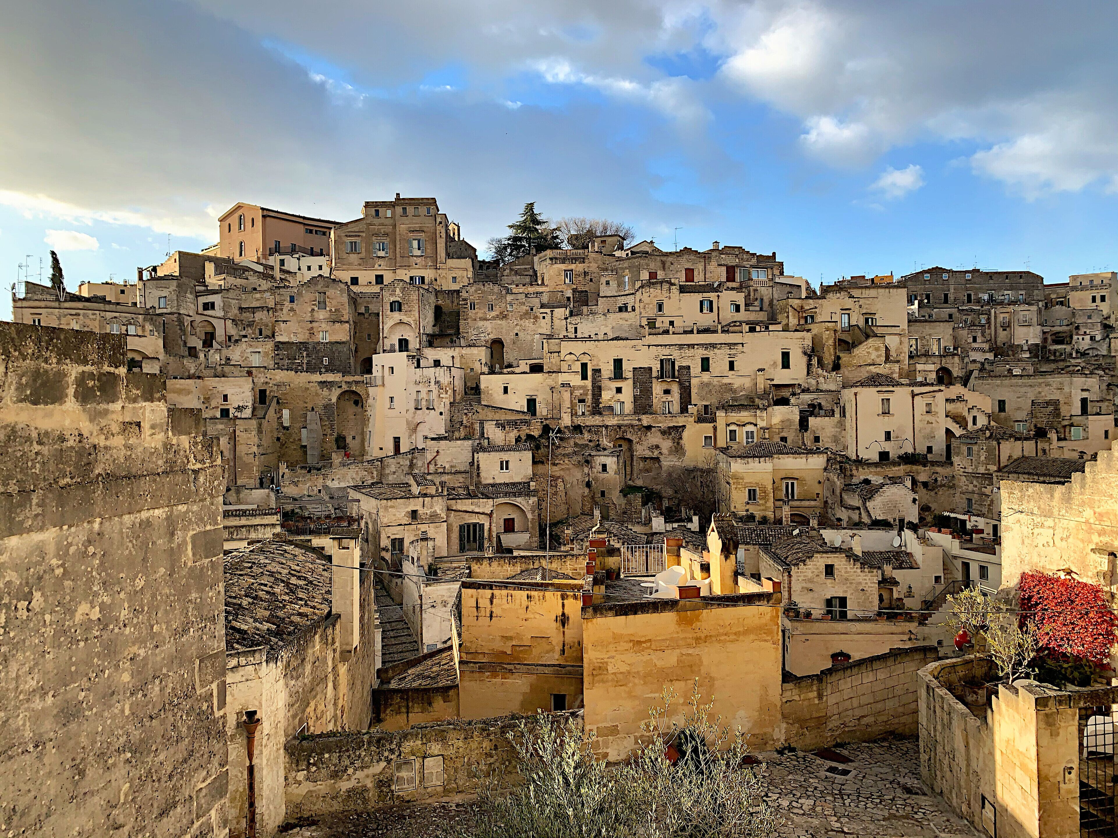 A densely packed hillside of historic stone buildings with terracotta roofs.