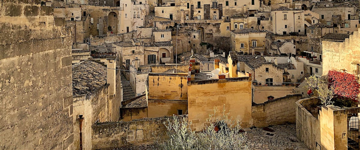 A densely packed hillside of historic stone buildings with terracotta roofs.