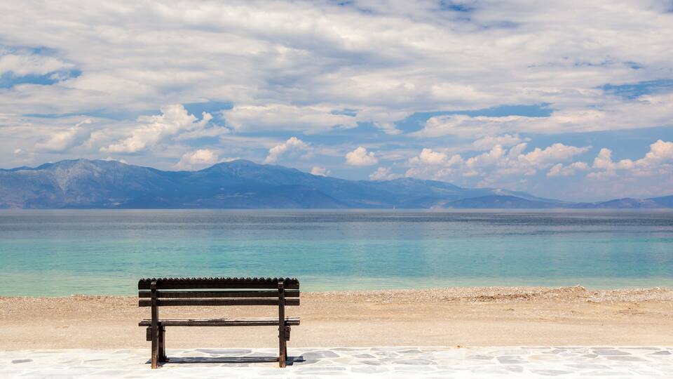 Empty wooden bench by the sea in a cloudy day, gazing the Corinthian gulf, near Xylokastro town, in Peloponnese, Greece.