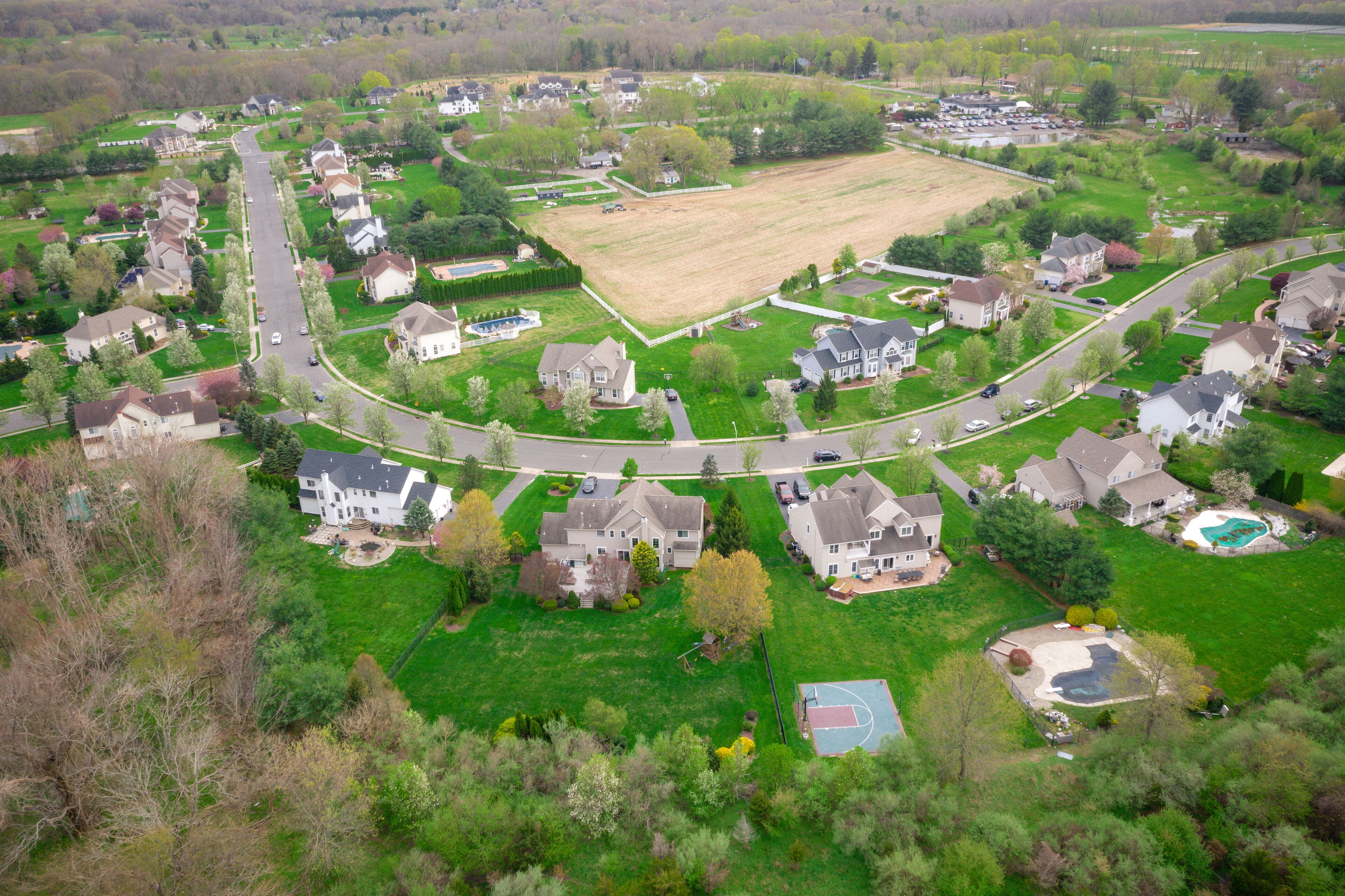 A suburban neighborhood with houses, a large open field, and a basketball court.