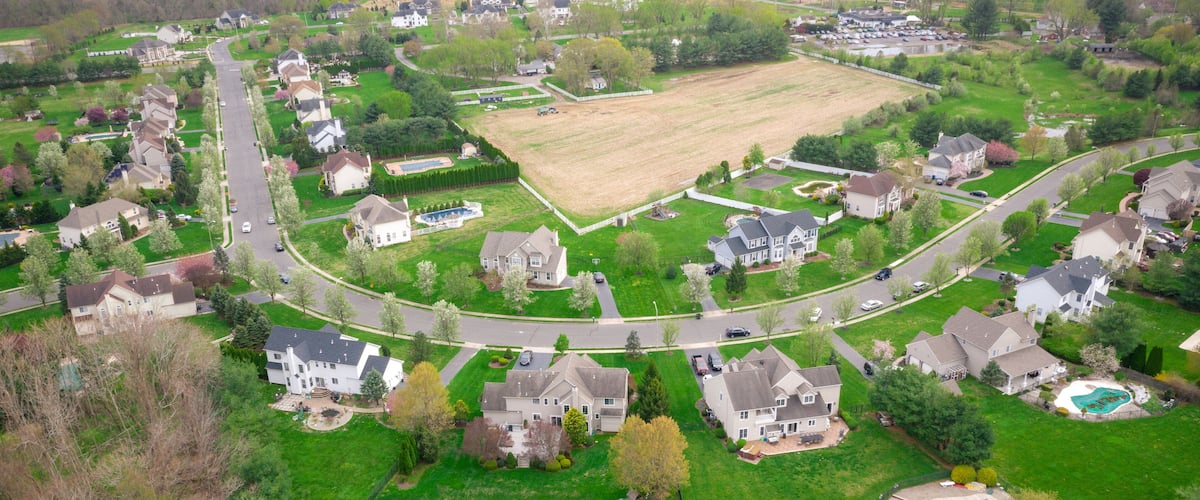 A suburban neighborhood with houses, a large open field, and a basketball court.