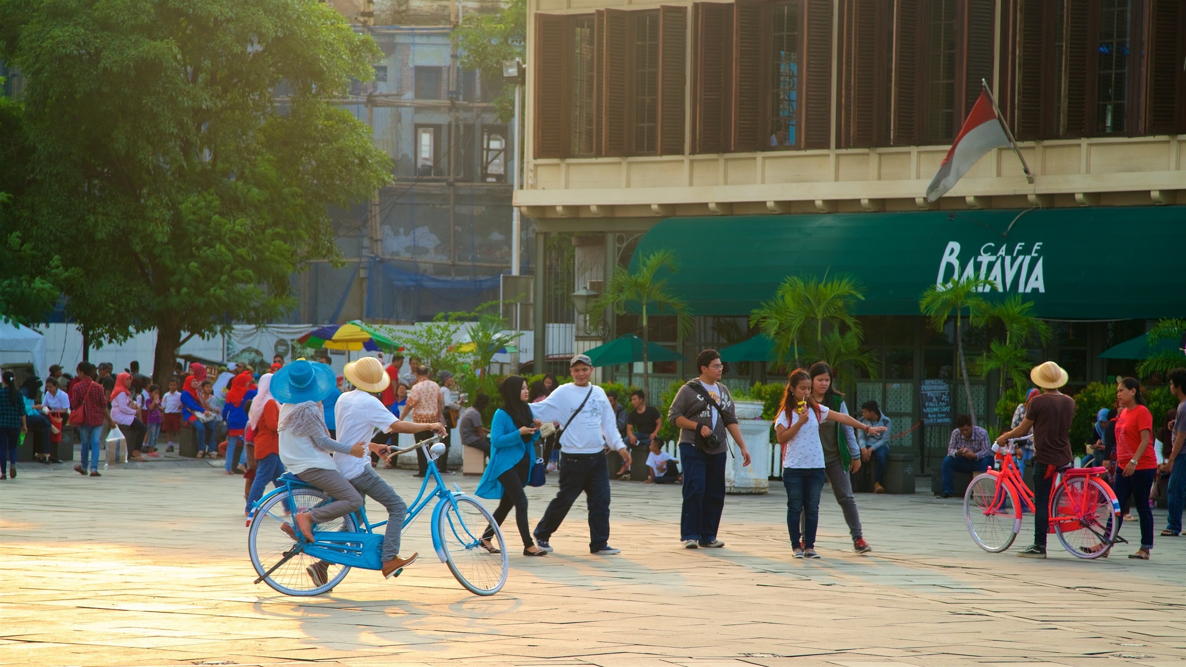 A busy public square with people walking and riding bicycles.