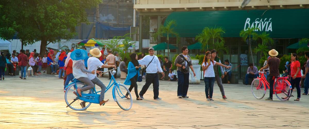 A busy public square with people walking and riding bicycles.