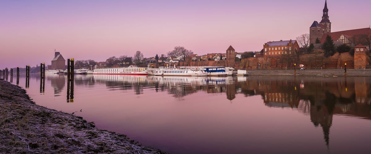 A river with boats, a church, and a tower.