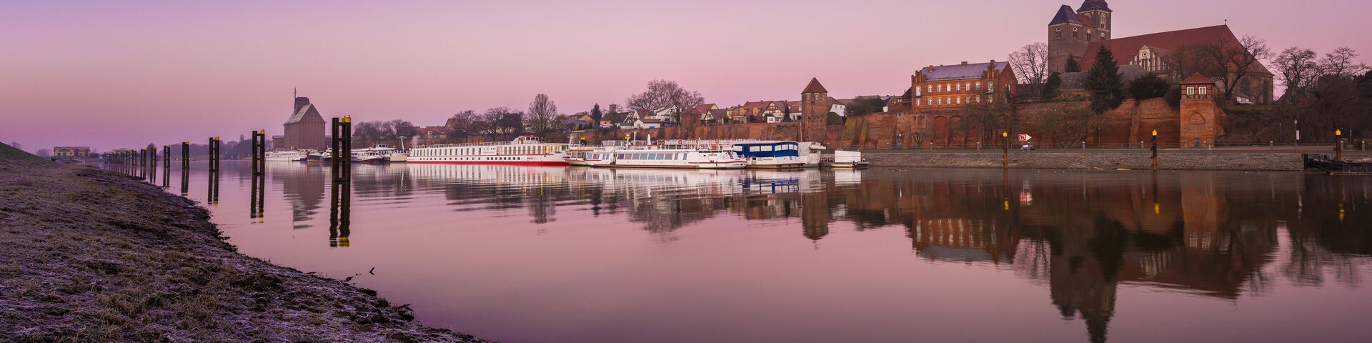 A river with boats, a church, and a tower.
