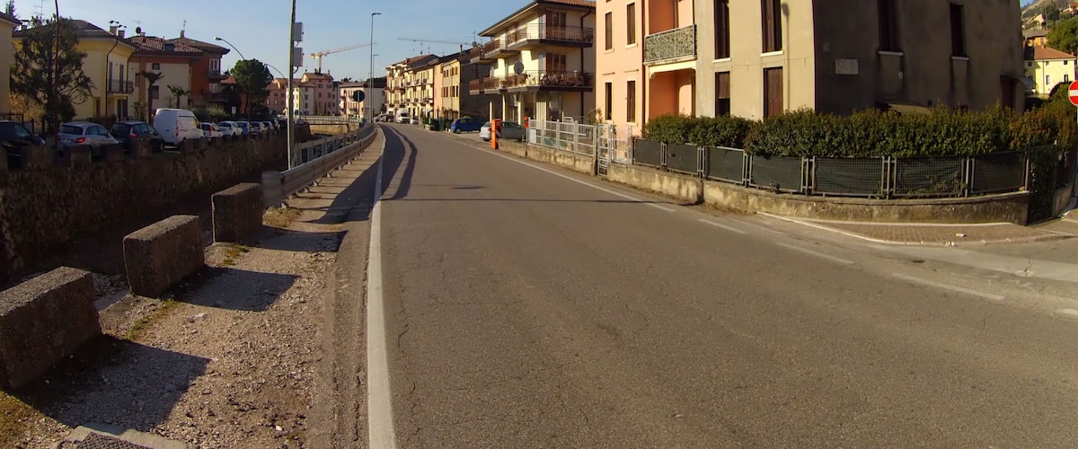 A quiet urban street with buildings, parked cars, and a clear sky.