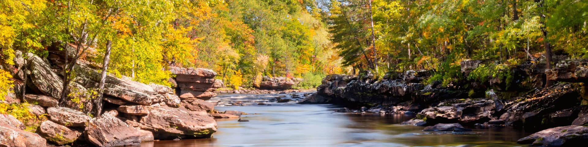 A river flowing through a forest with autumn foliage and rocky banks.