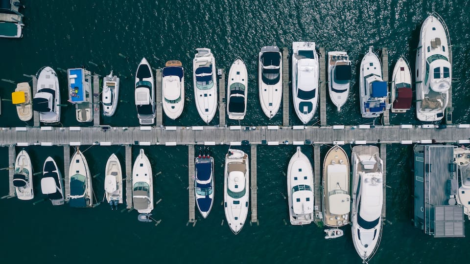 An aerial view of a marina with various boats docked at wooden piers.