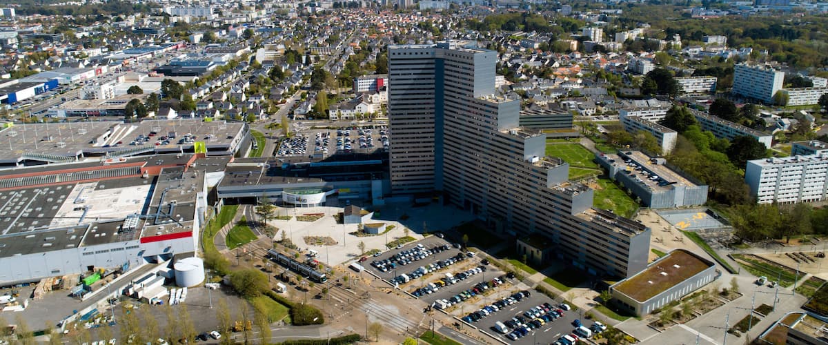 A cityscape with a prominent modern high-rise building, a parking lot, and surrounding residential areas.