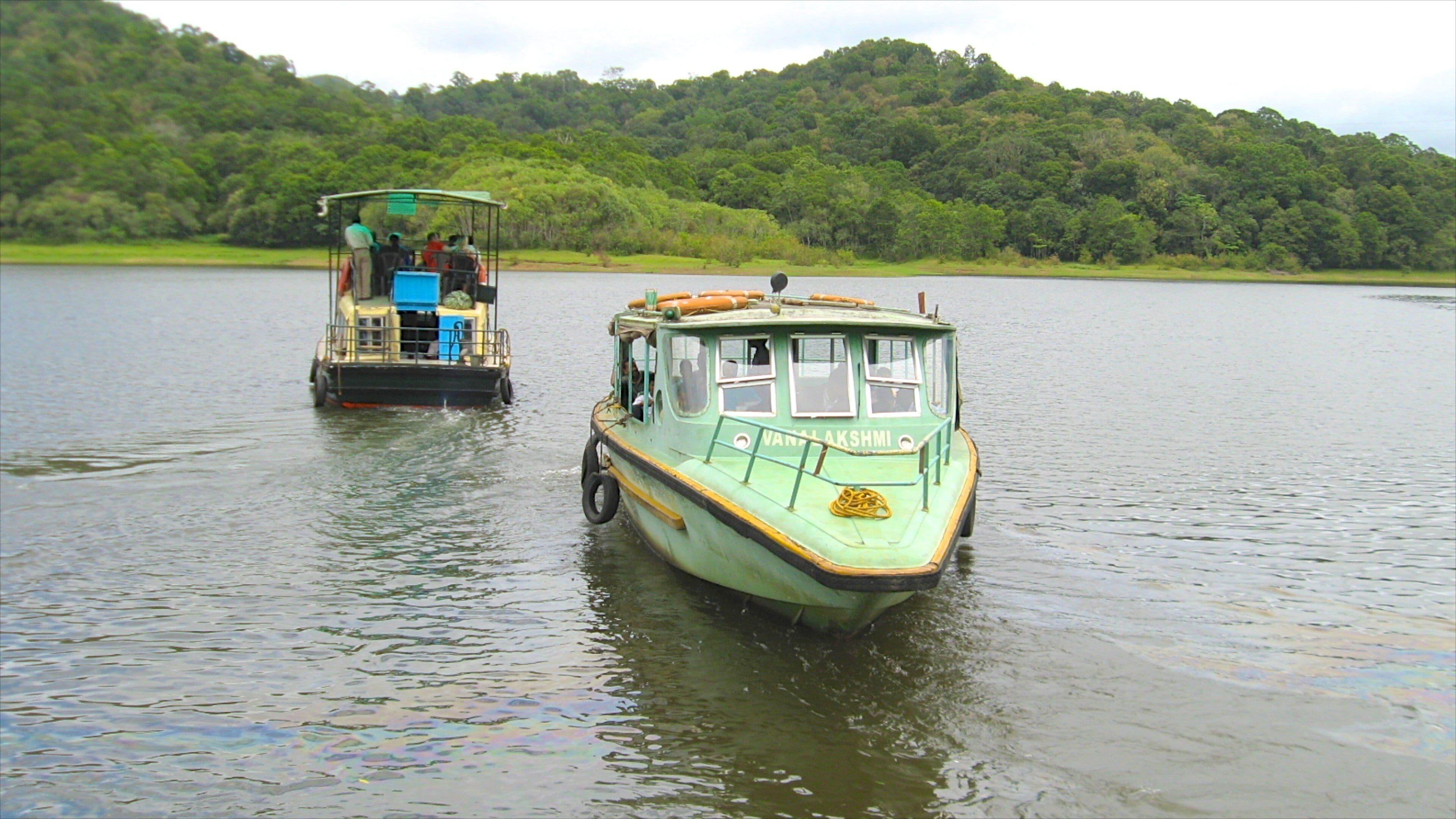 Two boats on a calm river surrounded by lush green hills.