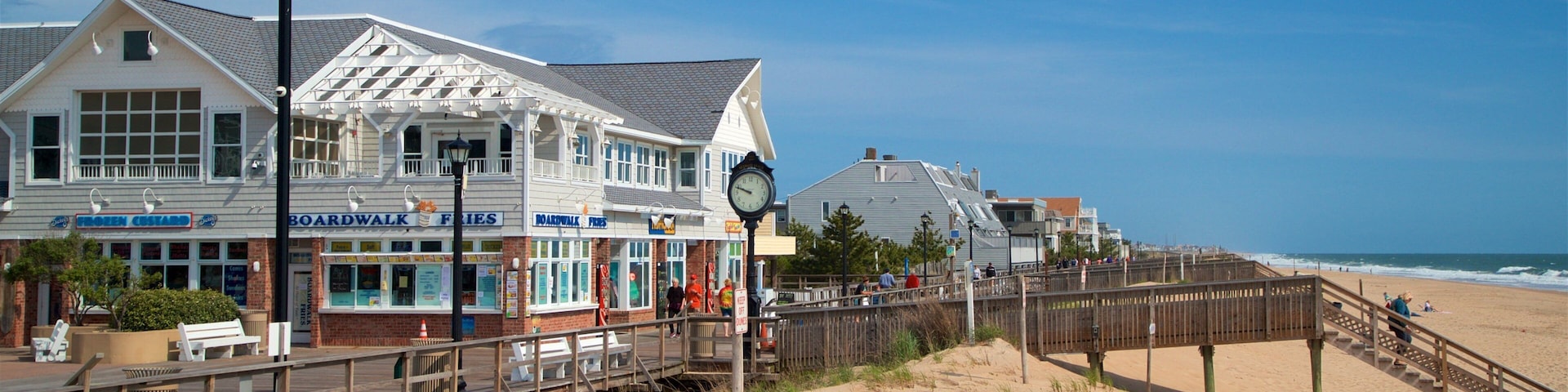 A boardwalk with shops, a clock, and a beach.