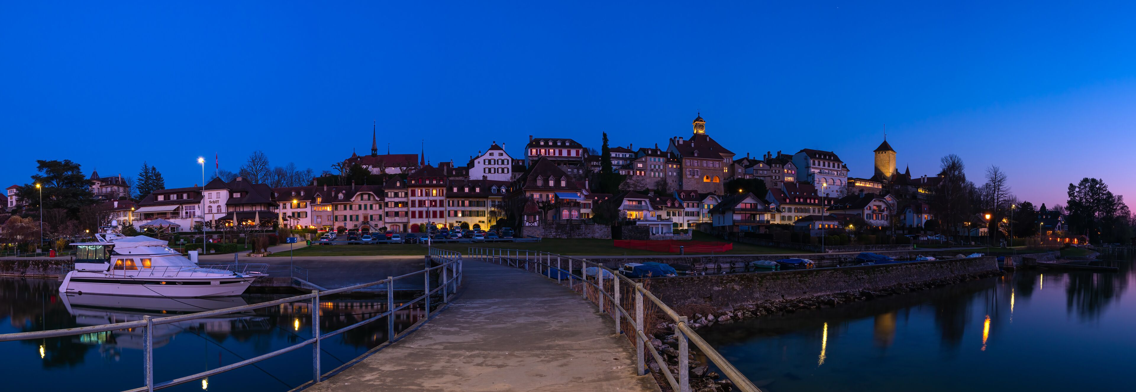 Murten, Switzerland - March 24.2022: Blue hour townscape panorama of medieval Murten or Morat, a bilingual municipality in the lake district of the canton of Fribourg.